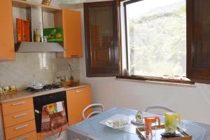 クストナーチにあるLa casa tra mare e collinaのキッチン(オレンジ色のキャビネット、テーブル、窓付)