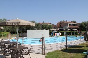 einen Pool mit Tischen und Sonnenschirmen neben einem Pool in der Unterkunft Villaggio Barbara in Moniga