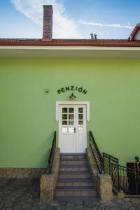 a green building with stairs leading to a white door at Penzión Kúria in Nové Mesto nad Váhom