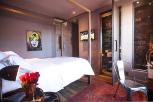 Un dormitorio con una cama blanca y una mesa con flores en The Grey Hotel, en Ciudad del Cabo