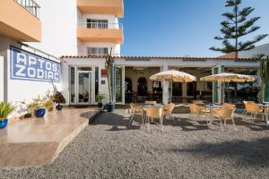 un patio con tavoli e ombrelloni di fronte a un edificio di Apartamentos Zodiac a Baia di Sant'Antoni