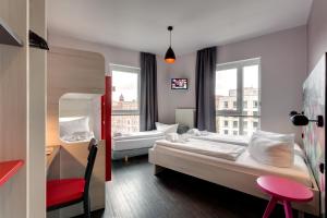 Una habitación de hotel con una cama, un escritorio y una ventana. en MEININGER Hotel Berlin Alexanderplatz, en Berlín