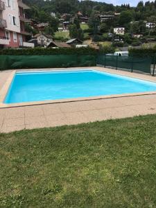 a large blue swimming pool next to a grass field at Le Grand Panorama No11 in Saint-Gervais-les-Bains