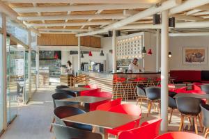 a restaurant with red chairs and tables and a counter at H10 Suites Lanzarote Gardens in Costa Teguise