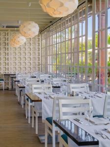 a restaurant with white tables and chairs and large windows at H10 Suites Lanzarote Gardens in Costa Teguise