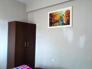 a painting hanging on a wall next to a bed at 1 BHK Deluxe Apartment in Candolim by GR Stays in Candolim