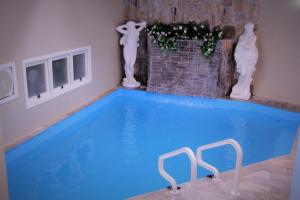 a swimming pool with two white statues in a room at Motel Avenida (Adult Only) in Gramado