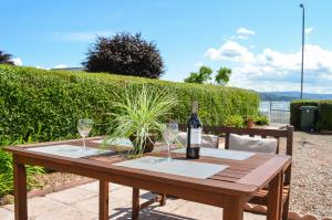 a wooden table with a bottle of wine and glasses at Sebright Holiday Apartment in Dunoon