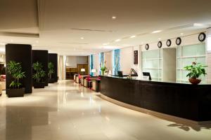 a lobby with a waiting area with plants and clocks at Occidental Sfax Centre in Sfax