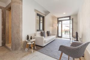 a living room with a white couch and chairs at BO - Marquês Apartments in Porto