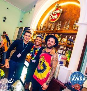un grupo de tres hombres parados frente a un bar en The Little Havana Party Hostel, en Cracovia