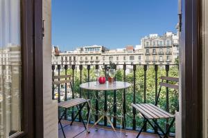 a table with a glass of wine on a balcony at Bcn Paseo De Gracia Rocamora Apartment in Barcelona