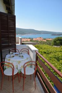 een tafel en stoelen op een balkon met uitzicht op het water bij Apartment Slavica in Kornić