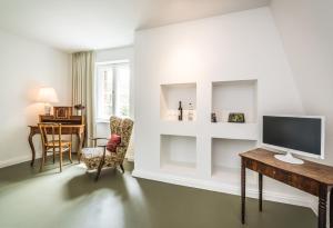 ein Wohnzimmer mit einem TV, einem Tisch und Stühlen in der Unterkunft Gäste- und Tagungshaus am Glockengarten in Berlin