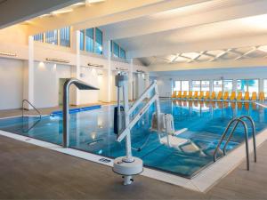 a large swimming pool with blue water in a building at Apart Dorfbäck in Kaunertal