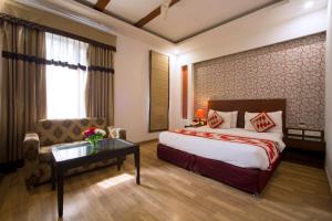 a hotel room with a bed and a couch and a table at Hotel Krishna - By RCG Hotels in New Delhi