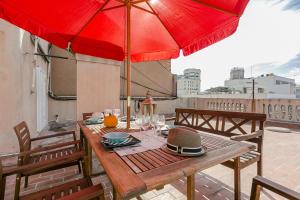 a wooden table with red umbrellas on a patio at Bcn Paseo De Gracia Rocamora Apartment in Barcelona