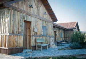 un edificio de madera con un banco fuera de él en El Rincon del Cerrillo, en Cortijo de Arriba