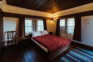 a bedroom with a bed with a red blanket and windows at Zoev House in Karlovo