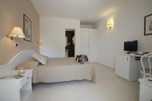a white bedroom with a bed and a television at Garden Hotel Ripa in Vieste