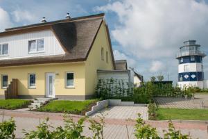 einem gelben Haus mit einem Leuchtturm im Hintergrund in der Unterkunft Ferienhaus Vermeer in Breege