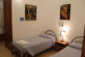 Zimmer mit 2 Betten und 2 Gemälden an der Wand in der Unterkunft Ospitalità San Tommaso d'Aquino in Bologna