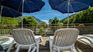 two white chairs and umbrellas on a wooden deck at Camping Al Lago Ledro in Ledro
