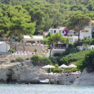 a beach with chairs and umbrellas on the water at Rosys Little Village in Skala