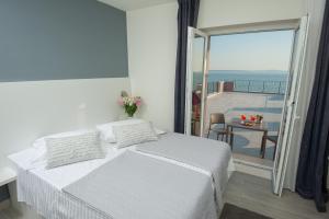 a white bedroom with a bed and a balcony at Seaside Luxury Suites in Podstrana