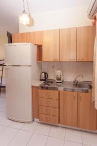 a kitchen with a white refrigerator and a sink at Ionio Sea Poros Studios in Mikros Gialos