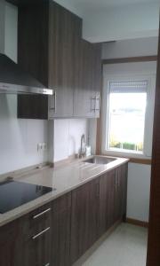 uma cozinha com armários de madeira, um lavatório e uma janela em Cancelas 94 em Santiago de Compostela