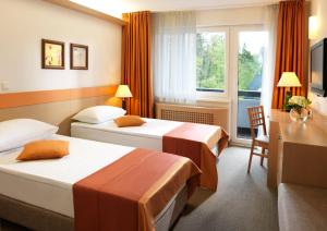 a hotel room with two beds and a desk at Garni Hotel Savica - Sava Hotels & Resorts in Bled