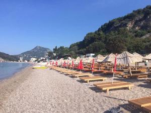 a beach with a bunch of umbrellas and benches at Holiday Home Aksentijevic in Sutomore