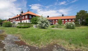 un grand bâtiment rouge et blanc avec une cour herbeuse dans l'établissement Fågelbrohus, à Värmdö