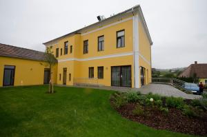 a large yellow house with a green yard at Papperl a' Pub in Schonberg am Kamp