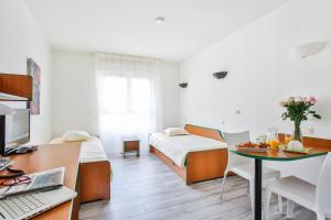 Cette chambre comprend deux lits et un bureau avec une table. dans l'établissement Hôtel et Résidence Les Lauréades Clermont-Ferrand Centre Jaude, à Clermont-Ferrand