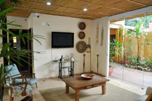 a living room with a table and a tv on the wall at Pousada Ilha Brazil in Ilhabela