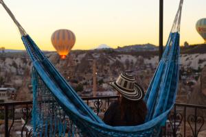 a person sitting in a hammock with hot air balloons at Tulip Cave Suites in Göreme
