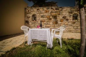 a table with a white table cloth and two chairs at Bodikos Villas & Apartments in Pitsidia