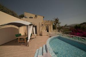 a house with a swimming pool next to a building at Bodikos Villas & Apartments in Pitsidia