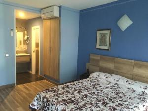 a bedroom with a bed and a blue wall at Hotel Don Angel in Villanueva de la Cañada