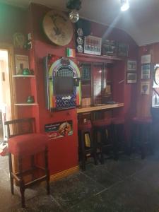 um bar com uma parede vermelha com bancos e uma televisão em O'Loughlin's Bar em Miltown Malbay