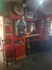 a bar with a red wall with stools and a tv at O'Loughlin's Bar in Miltown Malbay