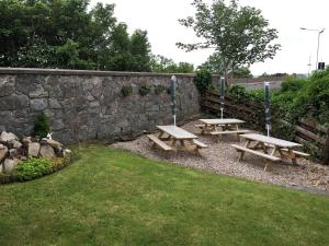 two picnic tables in front of a stone wall at Belgrave Arms Hotel in Helmsdale