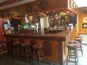 een houten bar met krukken in een kamer bij O'Loughlin's Bar in Miltown Malbay