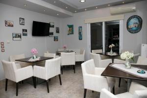 a dining room with tables and chairs and a tv at Arion Hotel in Skala Potamias
