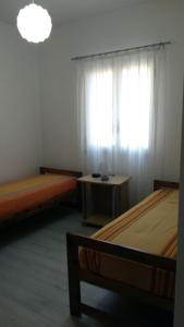 アルカモにあるFiori d'Ulivo Casa Vacanzaのベッド2台、テーブル、窓が備わる客室です。