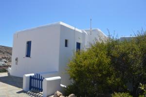 un edificio blanco con una valla azul delante de él en Superb view House-Sikinos Island-Chorio en Síkinos