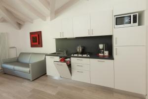 a kitchen with white cabinets and a chair and a microwave at Casa Carla in Nago-Torbole