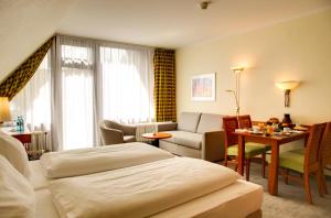 Una habitación de hotel con dos camas y una sala de estar. en H+ Hotel Willingen, en Willingen
